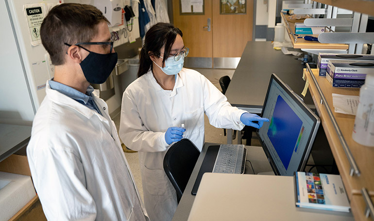 UBC researchers Nicolas Peleato and Li Ziyu examine the data after testing a water sample with a florescence spectrometer.